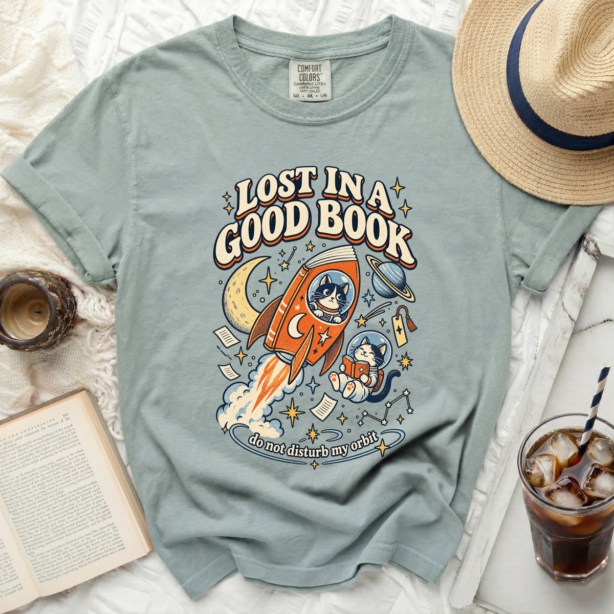Green t-shirt with "Lost in a Good Book" and space cats graphic.