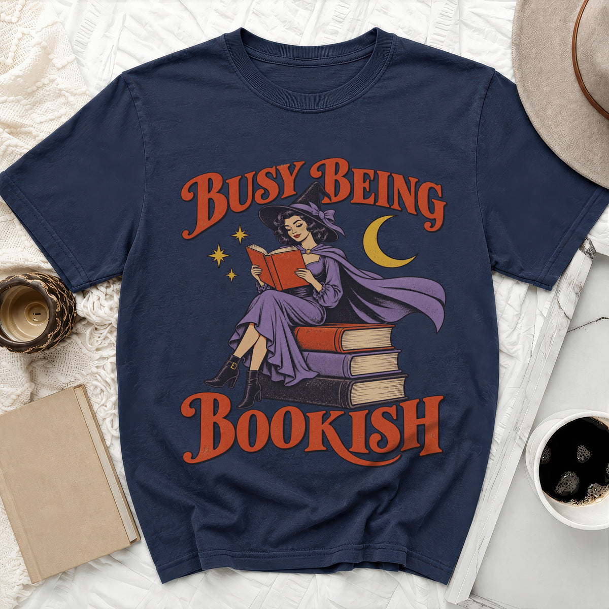 Navy t-shirt with witch reading books design and text "Busy Being Bookish".