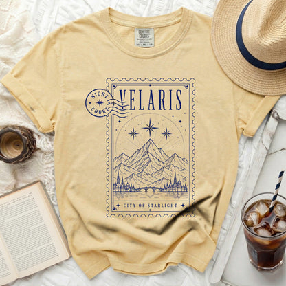 Yellow t-shirt with a blue stamp design featuring mountains and the text "Velaris City of Starlight".