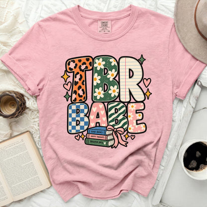 Pink t-shirt with "TBR BABE" text and stacked books graphic.