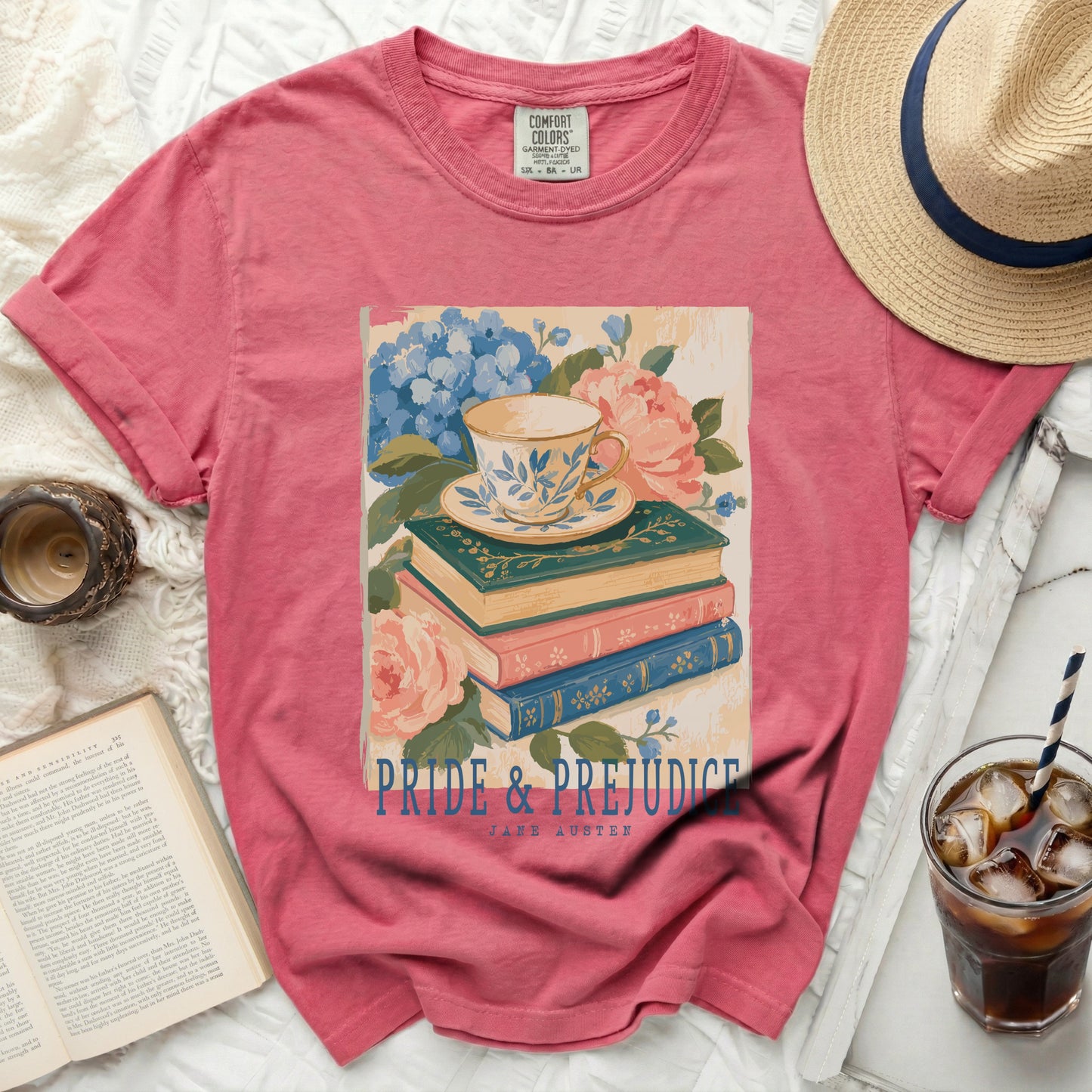 Pink t-shirt featuring "Pride and Prejudice" by Jane Austen with teacup and books graphic.