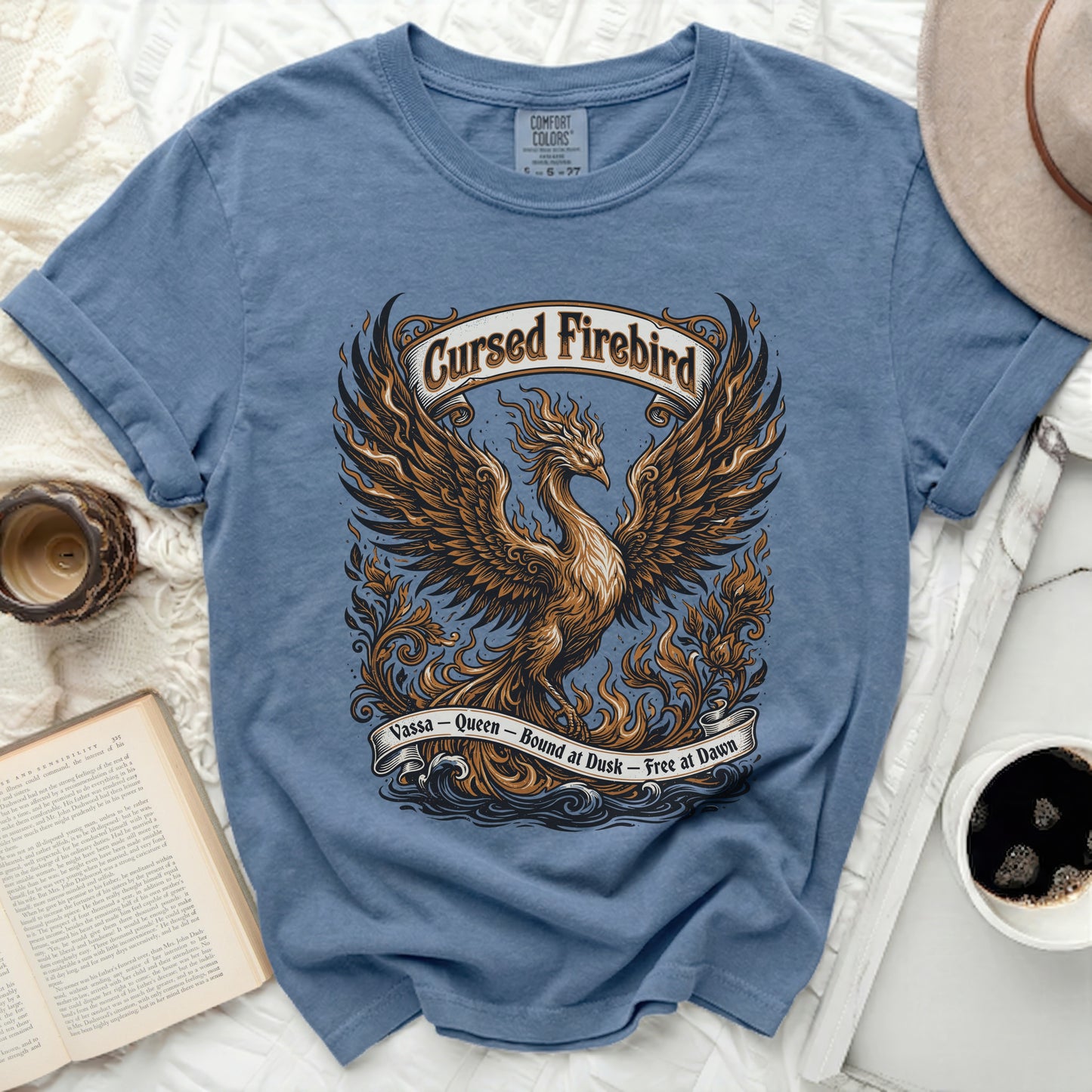 Blue t-shirt with a "Cursed Firebird" graphic, text "Vassa - Queen - Bound at Dusk - Free at Dawn".