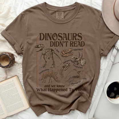 Brown t-shirt with dinosaur skeletons and text "Dinosaurs Didn't Read".