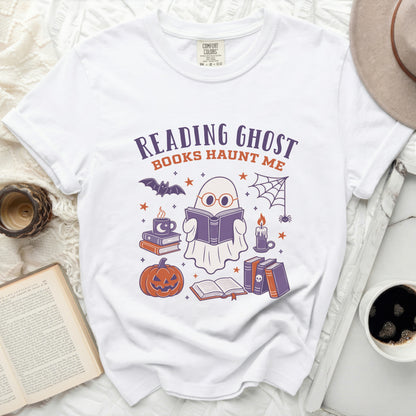 White t-shirt with a graphic of a ghost reading books and Halloween elements.