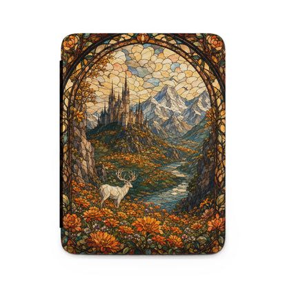 Stained glass art of a deer in a field before a castle and mountains.