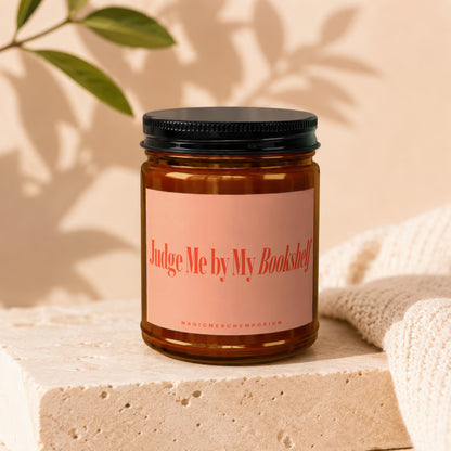 Amber jar candle with "Judge Me by My Bookshelf" text on a peach label.