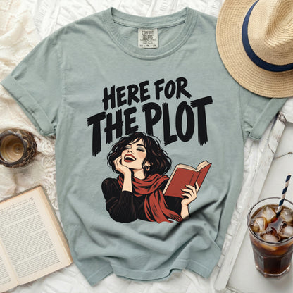 T-shirt with "Here for the Plot" text and illustrated woman reading a book.