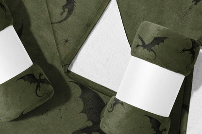 Green fleece blanket with dark dragon pattern, rolled and banded.
