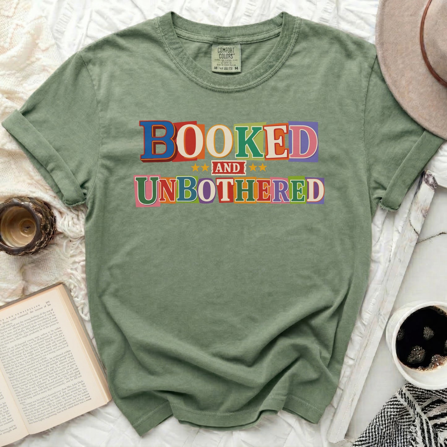 Green t-shirt with "Booked and Unbothered" in colorful block letters.
