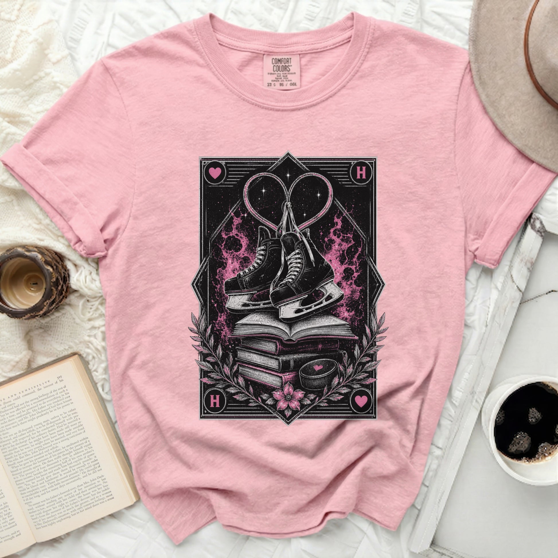 Pink t-shirt with ice skates, hearts, and stacked books graphic.