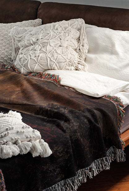 a cozy and inviting bedroom scene, featuring a brown leather couch with a white throw blanket and a white pillow. The blanket has a dark, textured pattern, while the pillow has a white, braided design. The overall color scheme is a mix of brown, white, and black, creating a warm and comfortable atmosphere.