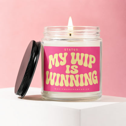 Candle with a pink label that reads "STATUS: MY WIP IS WINNING".