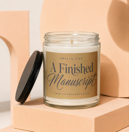 Glass candle with gold label that reads "Smells Like A Finished Manuscript".