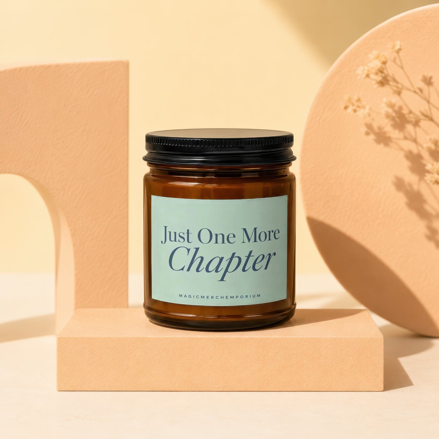 Amber jar candle with black lid and light blue label reading "Just One More Chapter".