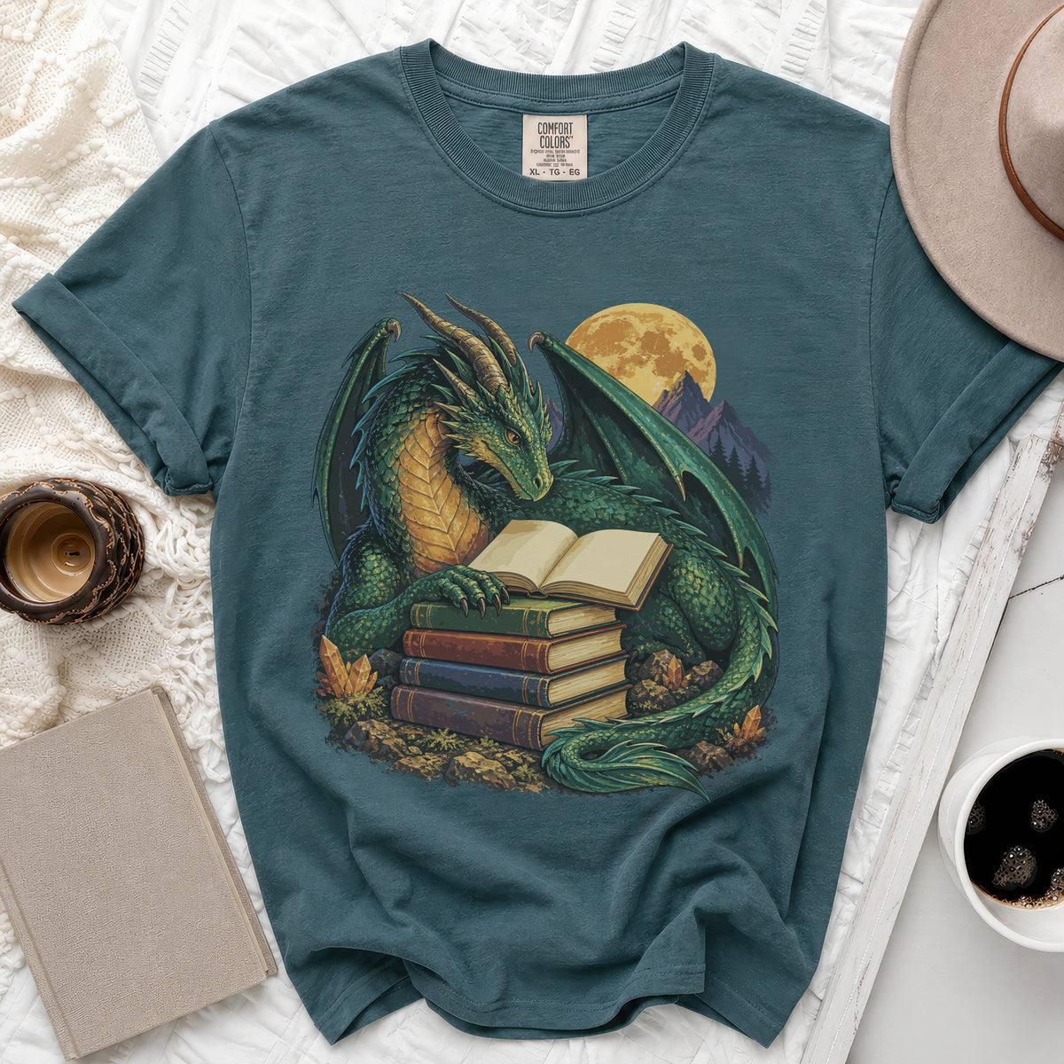 Teal t-shirt with a green dragon reading books in front of a full moon.