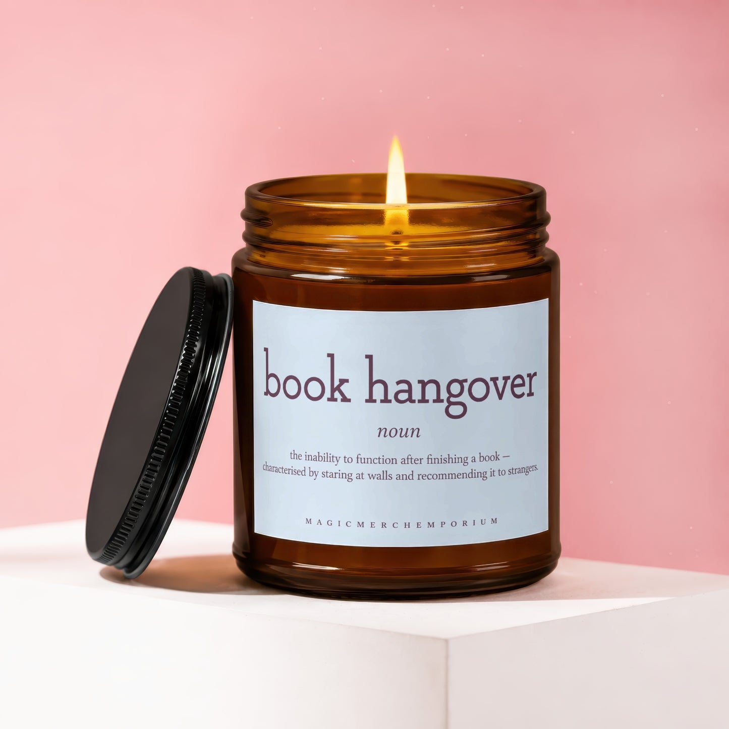 Brown glass candle with lit flame, "book hangover" definition on label.