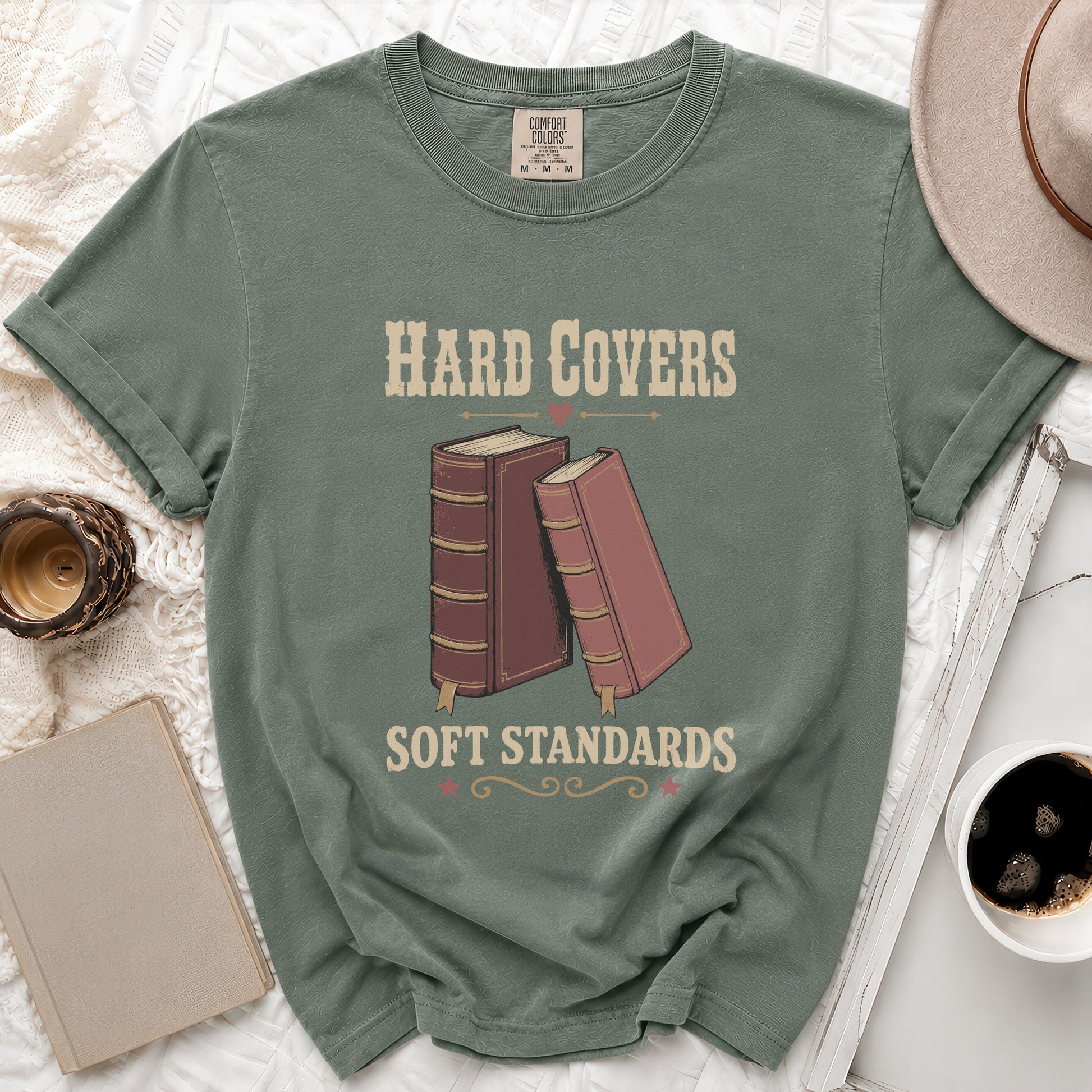 Green t-shirt with "Hard Covers Soft Standards" text and vintage book graphics.