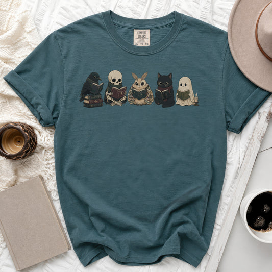 Teal t-shirt with a print of a crow, skeleton, moth, cat, and ghost reading books.