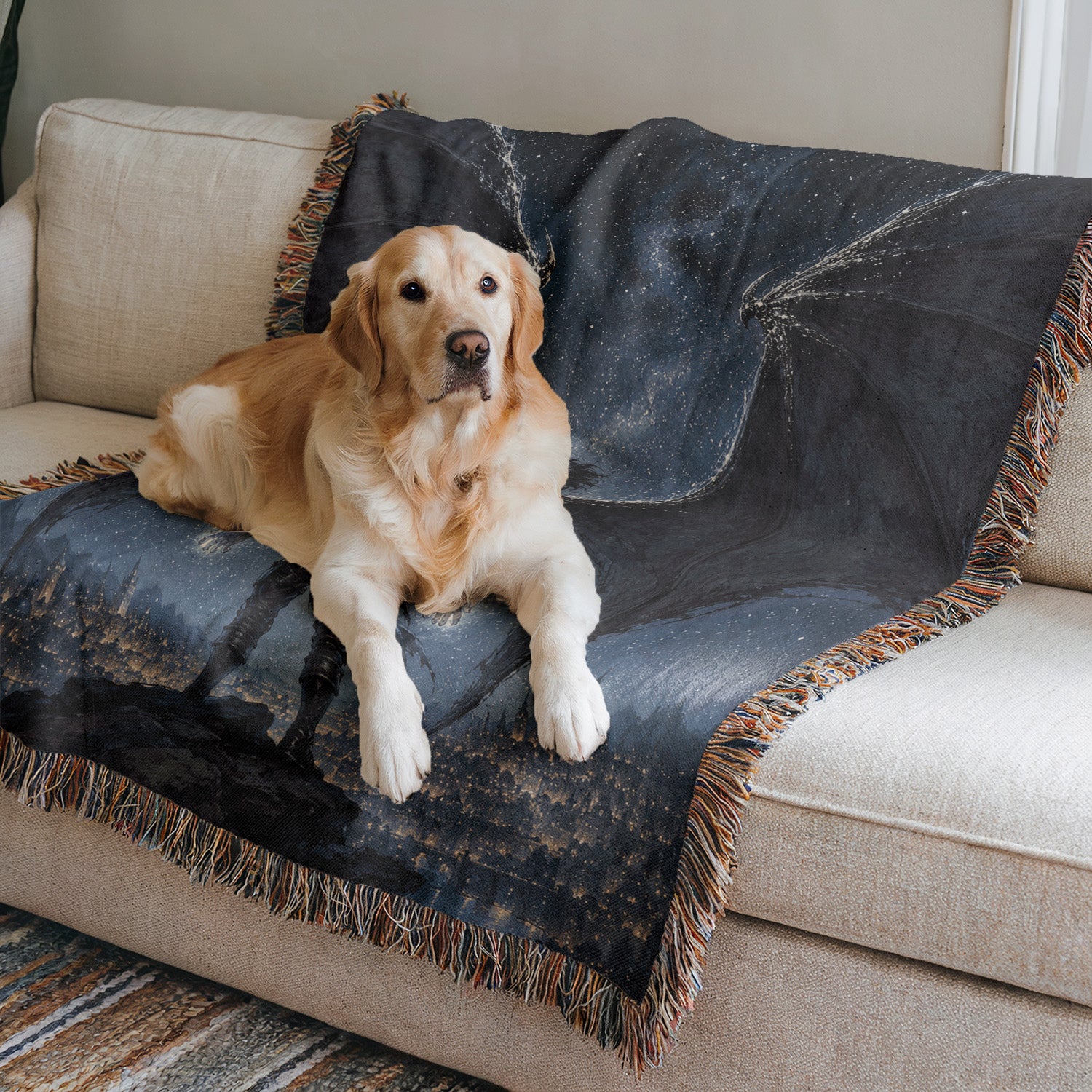 A golden retriever dog is lying on a blue and black blanket on a beige couch, looking directly at the camera.