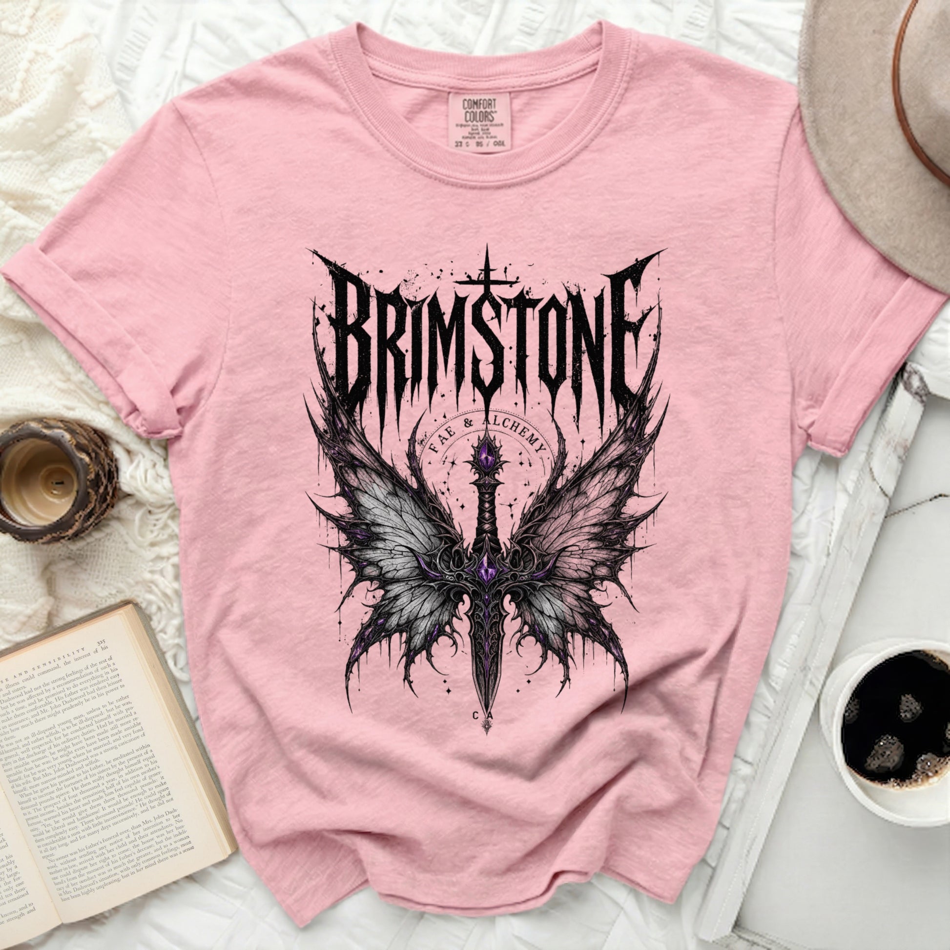 Pink t-shirt with "BRIMSTONE FAE & ALCHEMY" and winged dagger graphic.