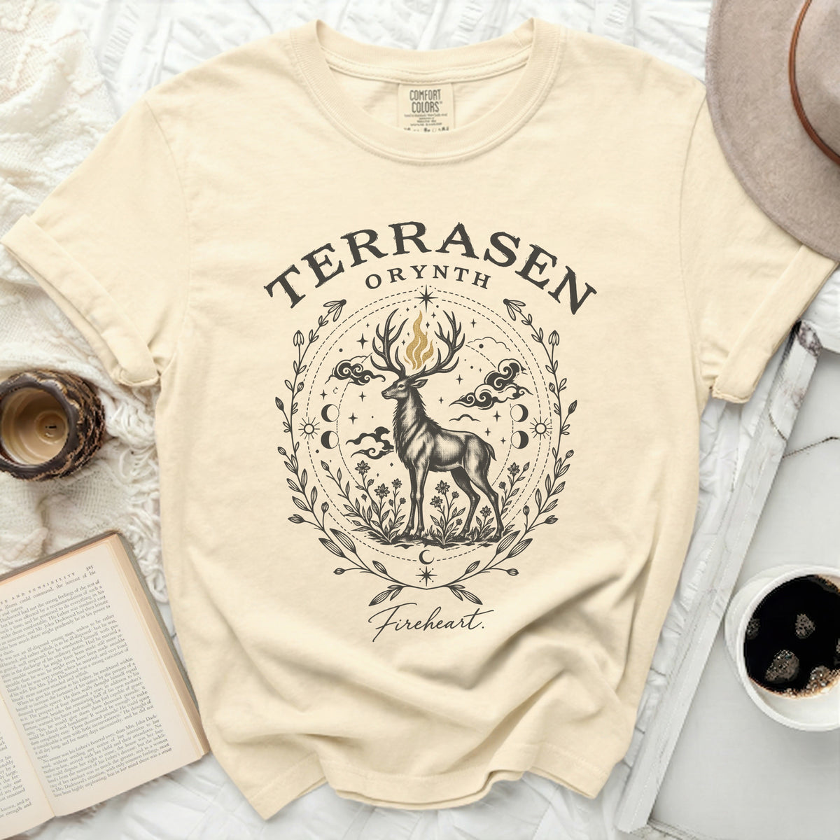 Beige t-shirt featuring a black graphic of a stag with flames on antlers and text "Terrasen Orynth Fireheart".