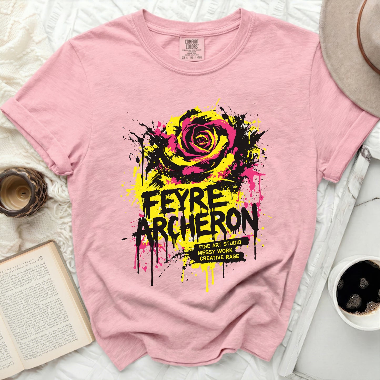 Pink t-shirt with yellow and black rose graphic and bold text.