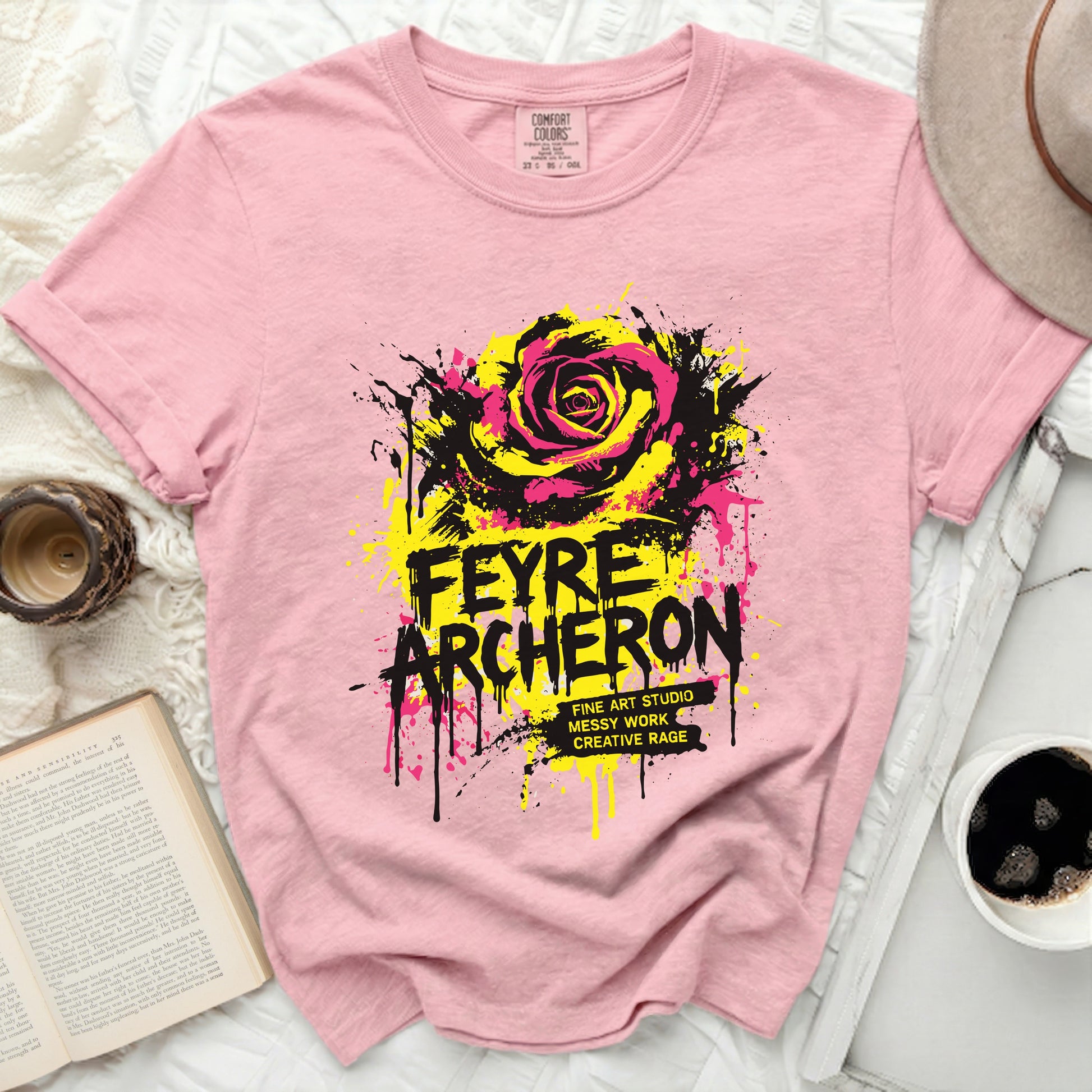 Pink t-shirt with yellow and black rose graphic and bold text.