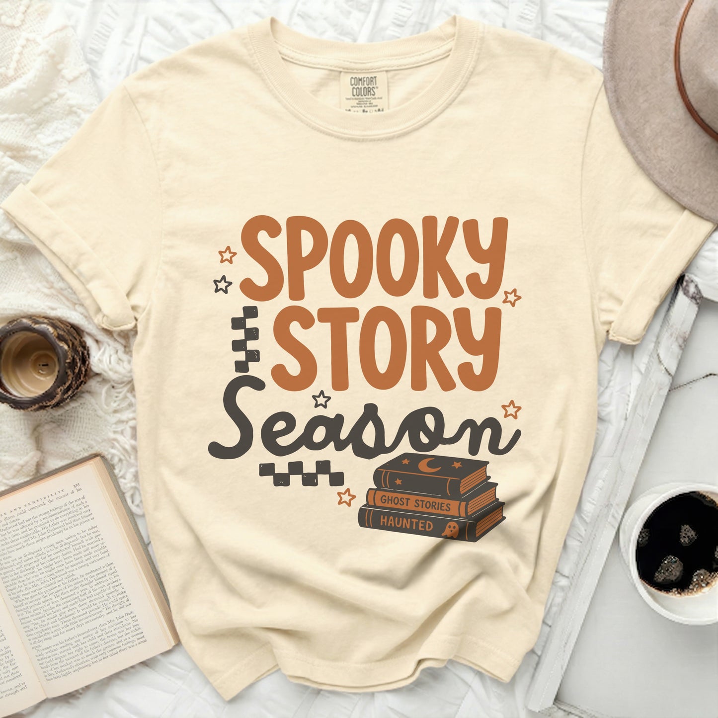 Cream t-shirt with "Spooky Story Season" graphic and stack of Halloween books.
