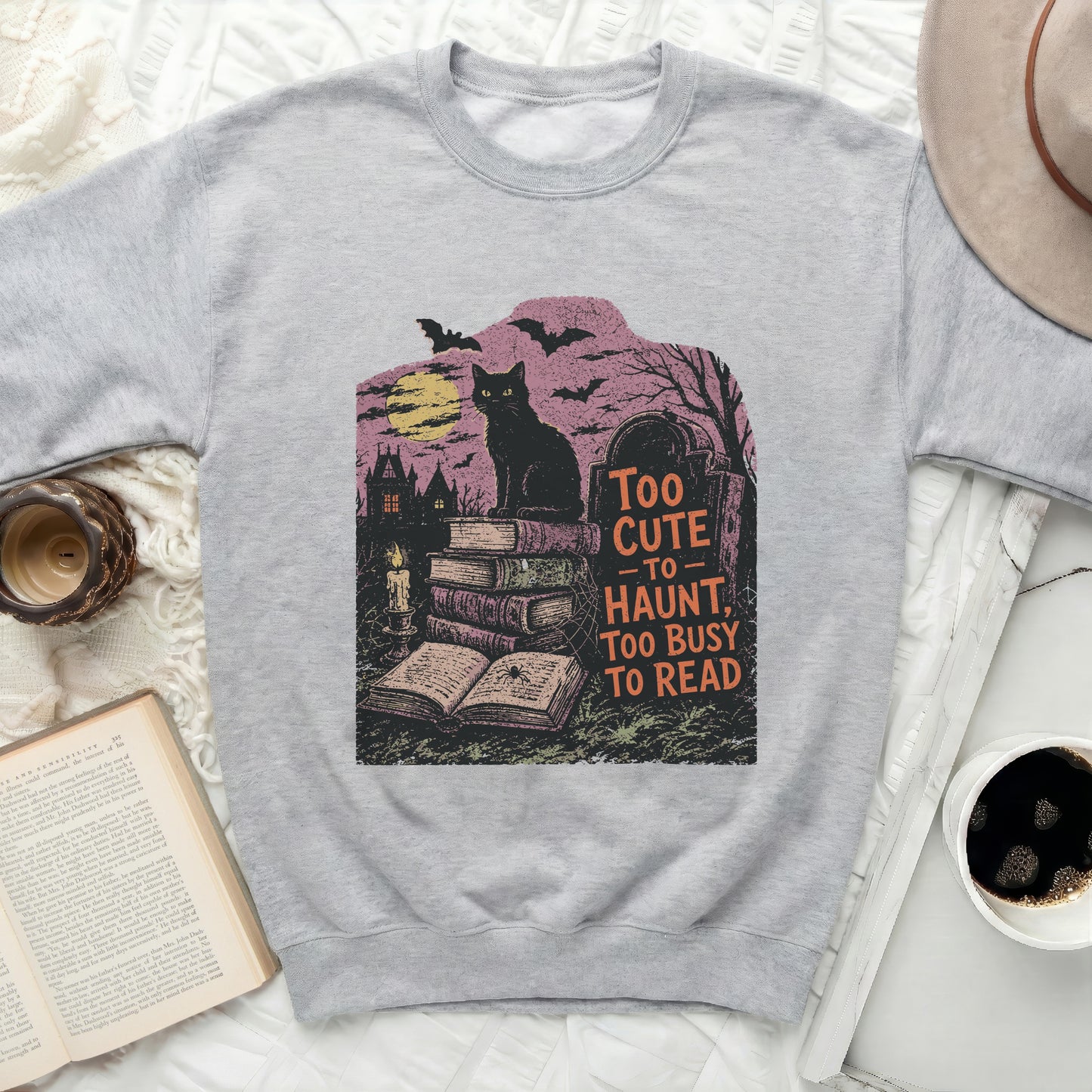 Grey sweatshirt with black cat, books, and text "Too cute to haunt, too busy to read"