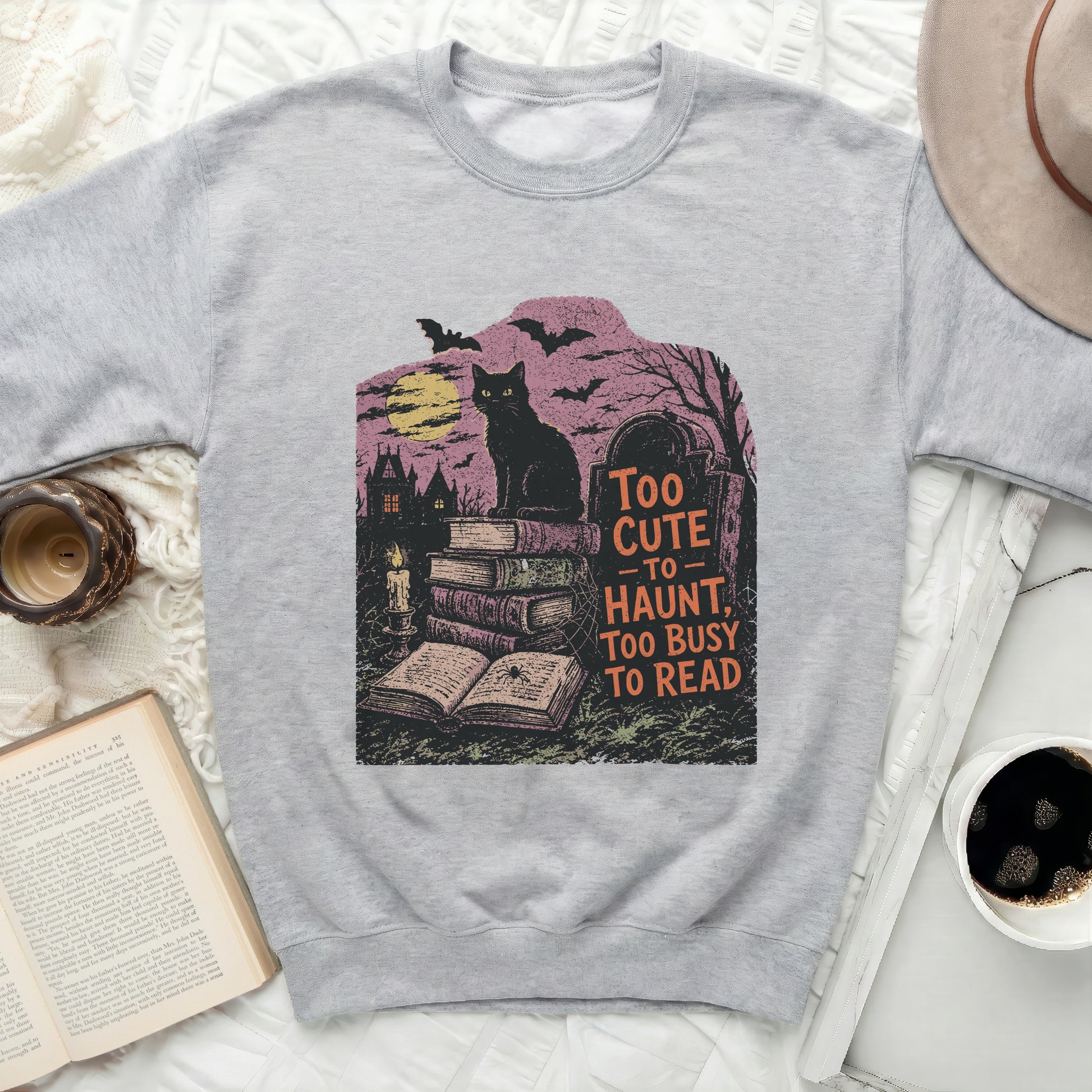 Grey sweatshirt with black cat, books, and text "Too cute to haunt, too busy to read"