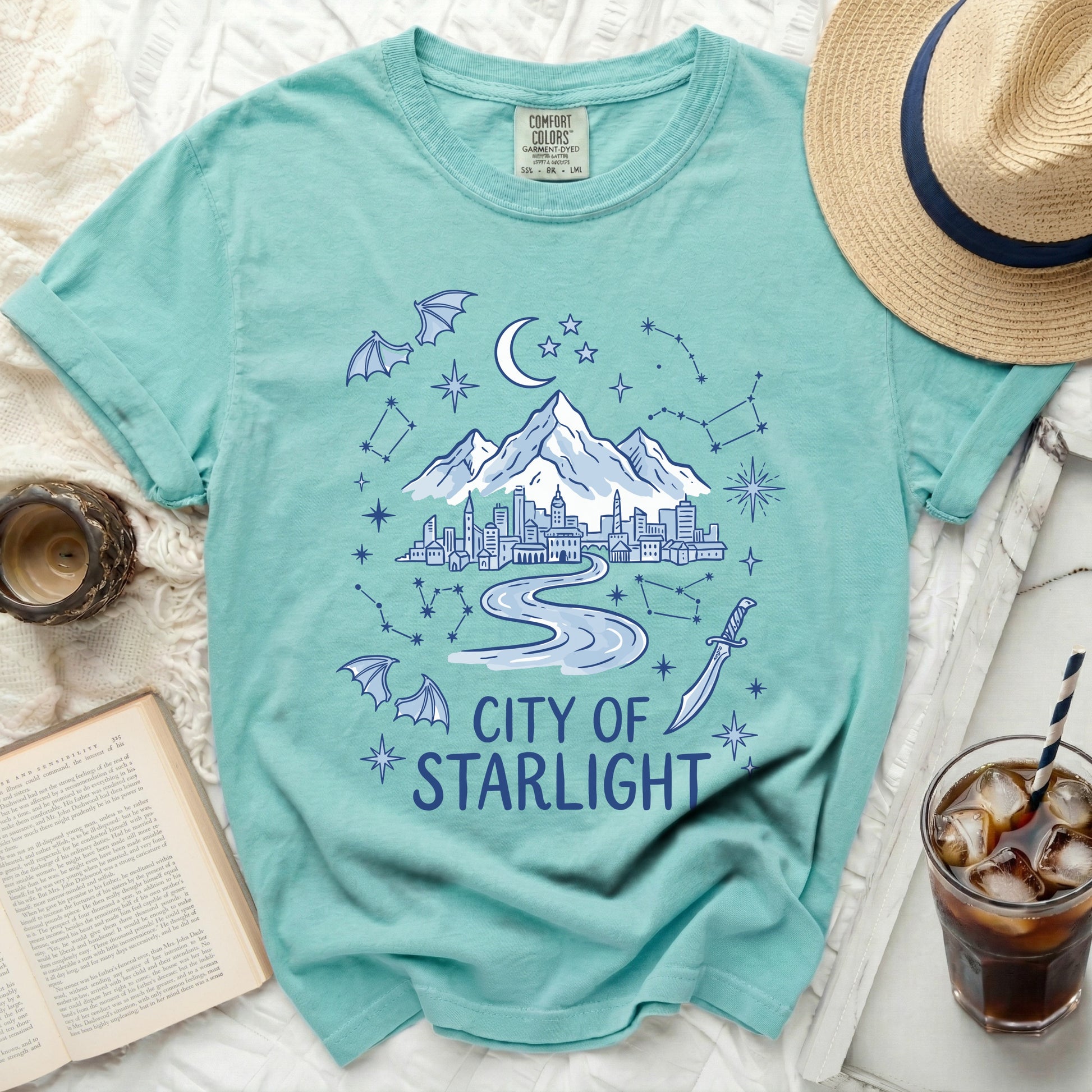 Teal t-shirt with "City of Starlight" graphic featuring a city, mountains, moon, stars, bats, and sword.