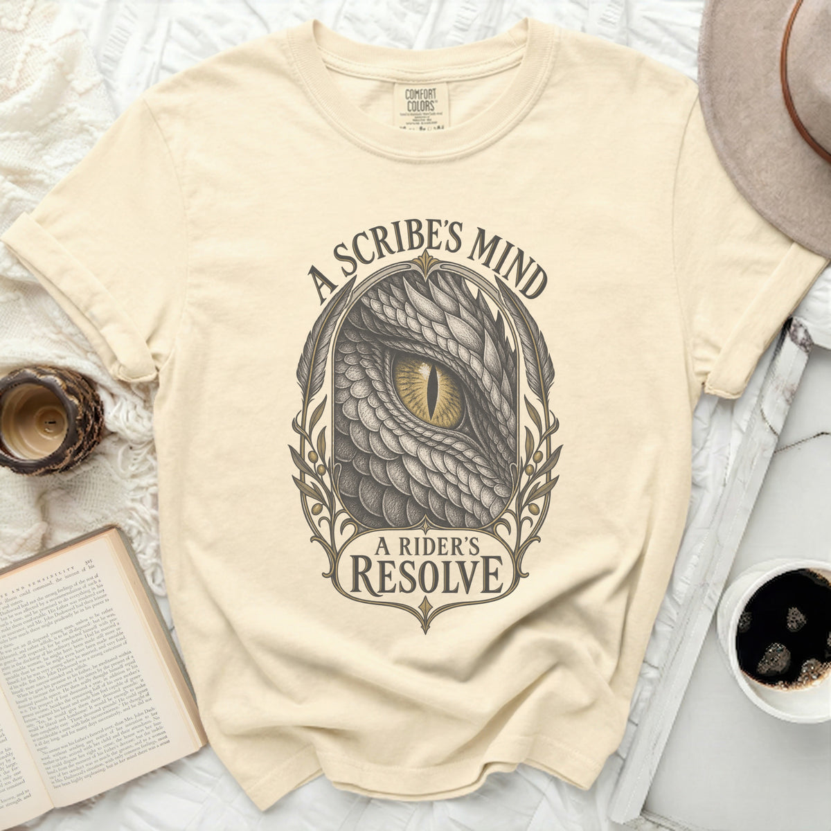 Cream t-shirt with a dragon's eye and "A Scribe's Mind, A Rider's Resolve" text.