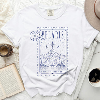 White t-shirt with blue graphic of mountains, city, and stars in a stamp design.