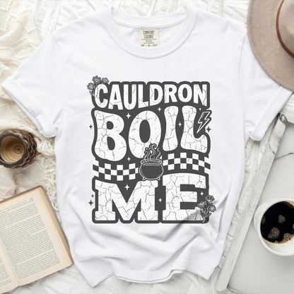 White t-shirt with "Cauldron Boil Me" graphic, cauldron, and flowers.