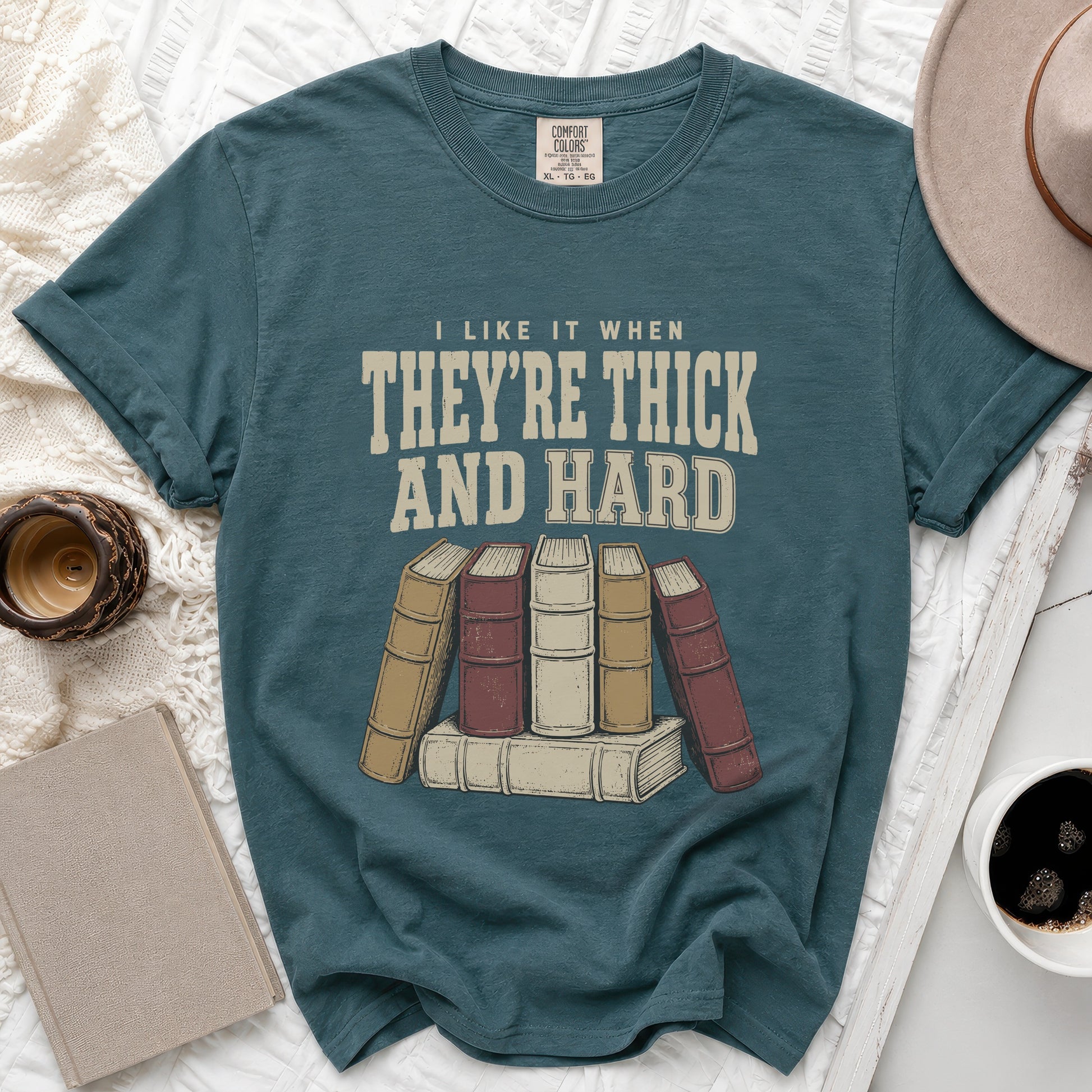 Teal t-shirt with text "I like it when they're thick and hard" and illustration of books.