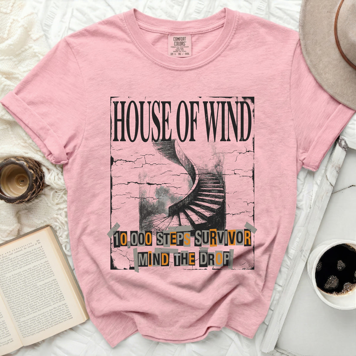Pink t-shirt with "House of Wind" and a spiral staircase graphic.