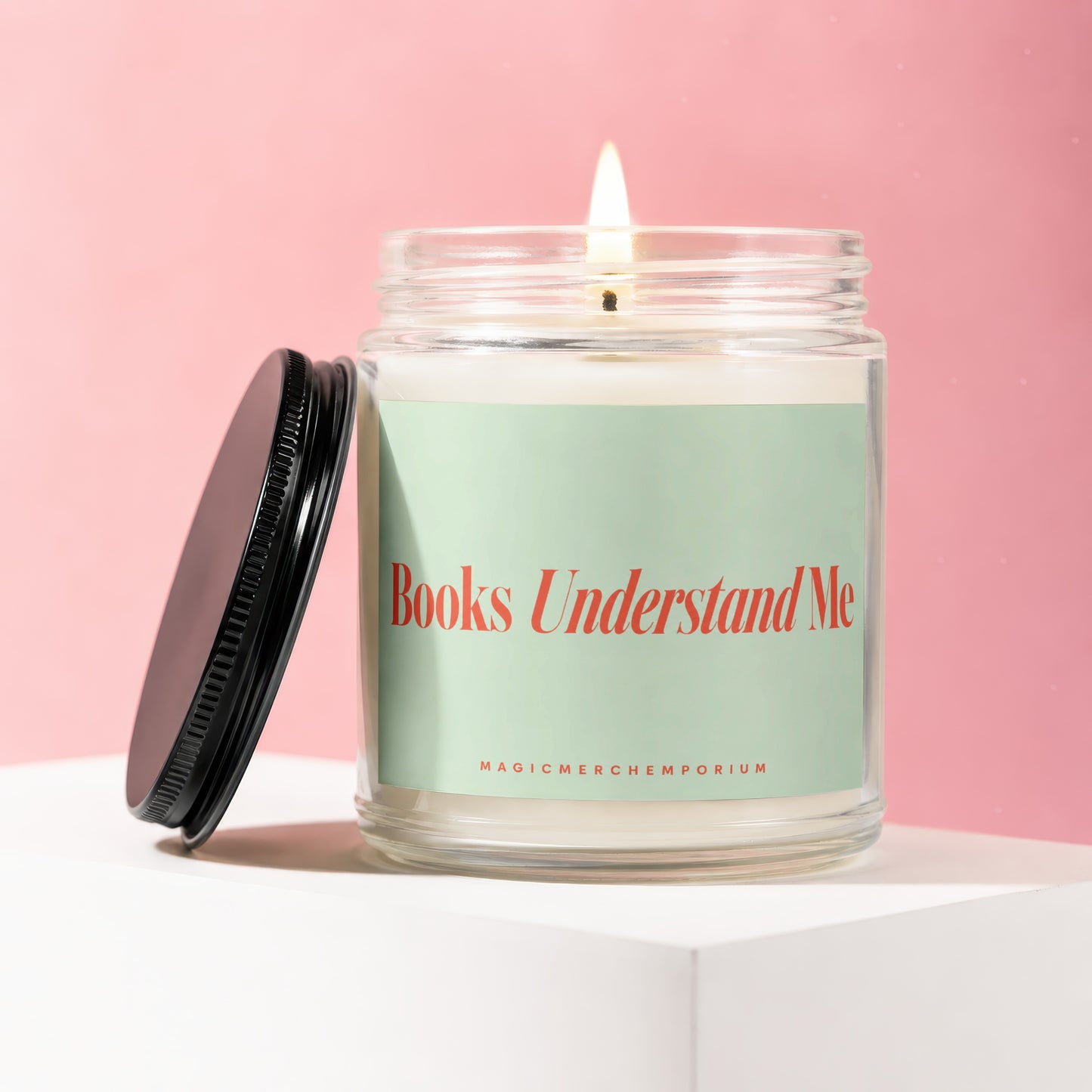 A lit candle in a jar with a light green label saying "Books Understand Me".