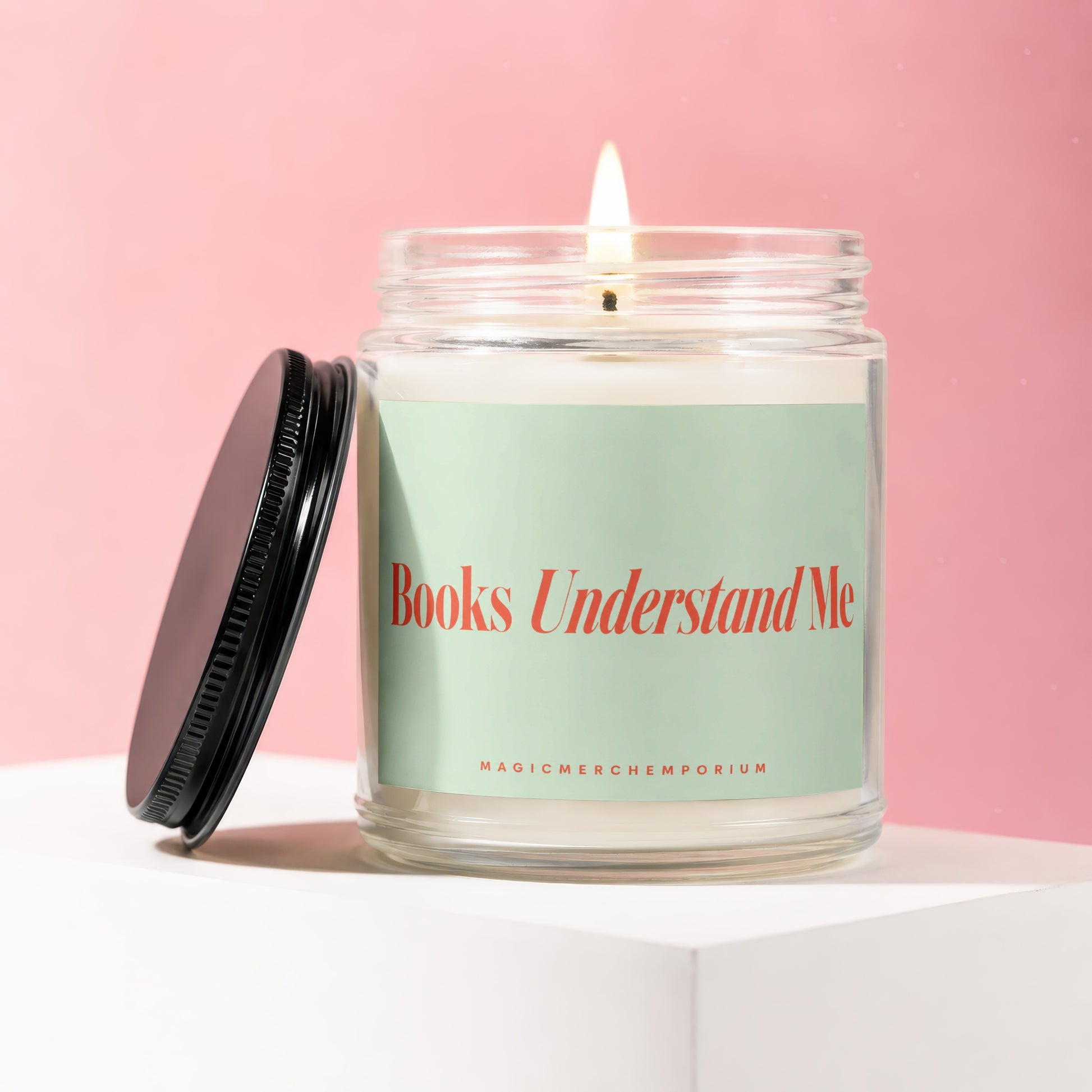 A lit candle in a jar with a light green label saying "Books Understand Me".