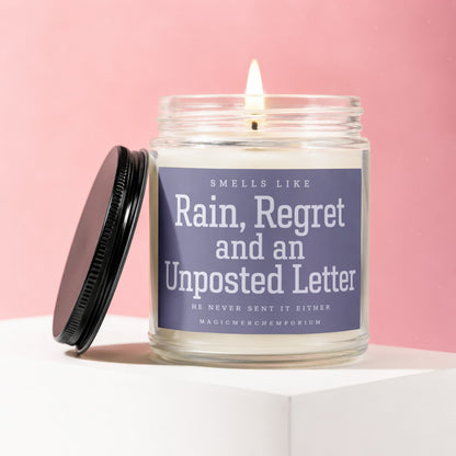 Glass candle with label "Smells Like Rain, Regret and an Unposted Letter".