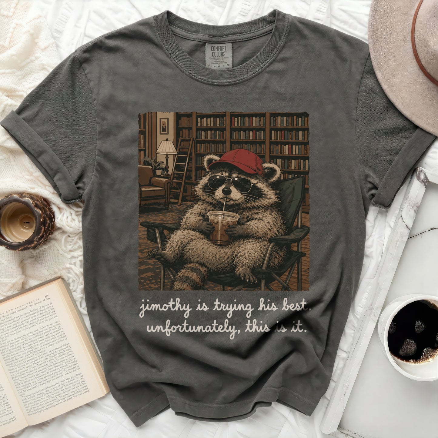T-shirt with a raccoon wearing a hat and sunglasses, sitting in a chair.
