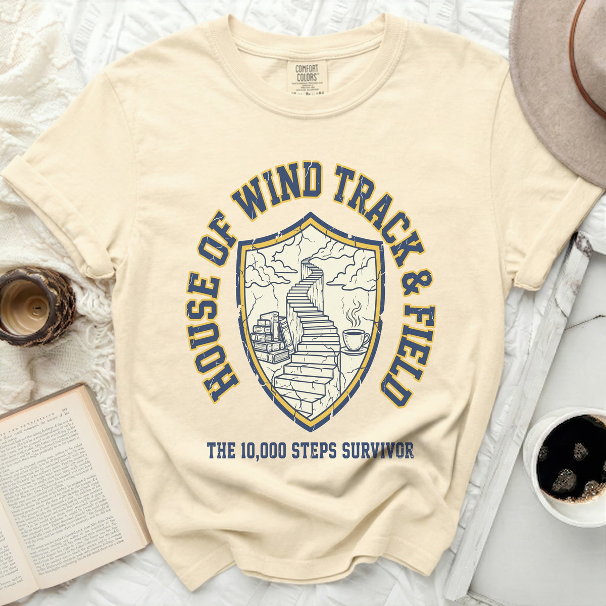 Cream t-shirt with shield graphic: "House of Wind Track & Field The 10,000 Steps Survivor"