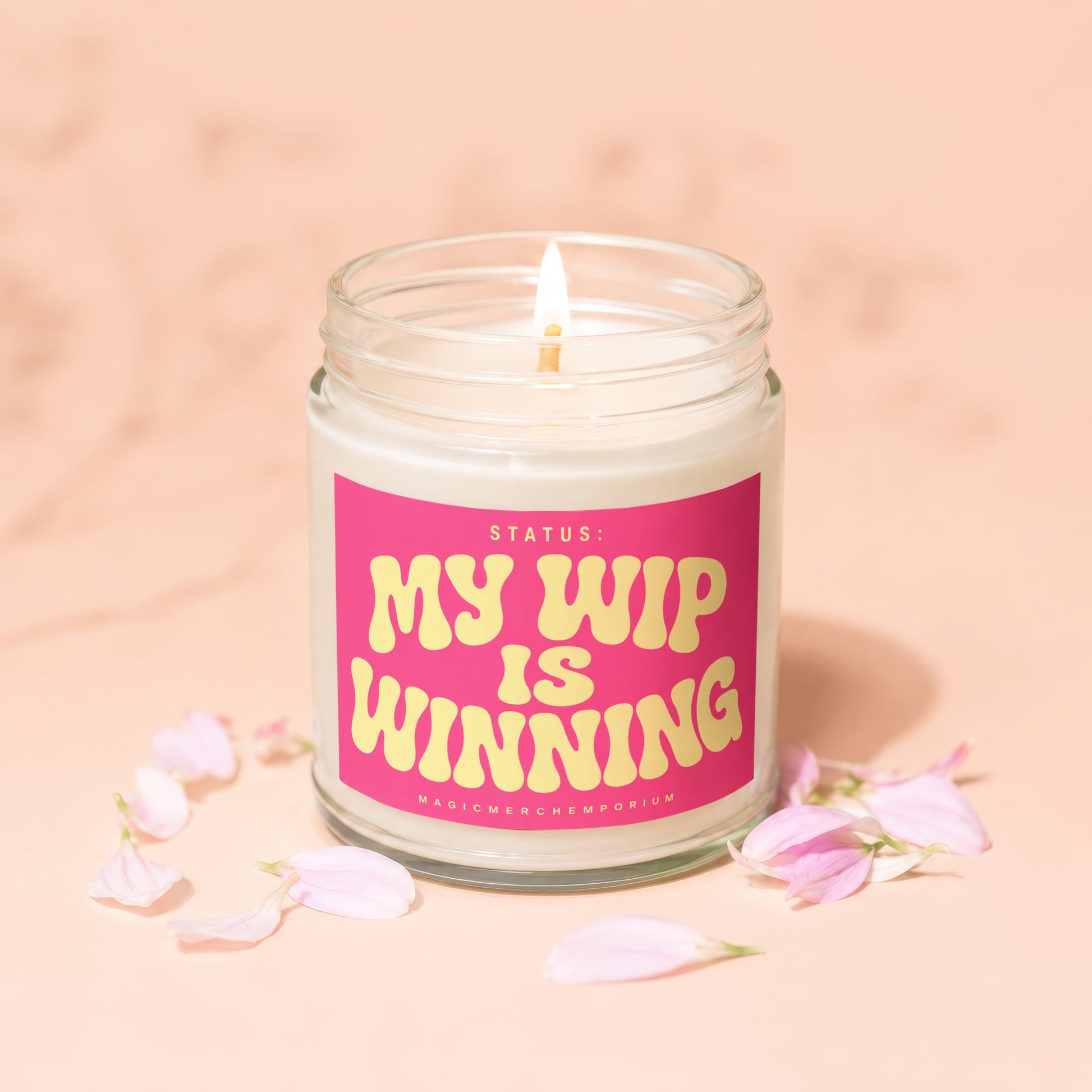 Glass jar candle with pink label reading "STATUS: MY WIP IS WINNING"