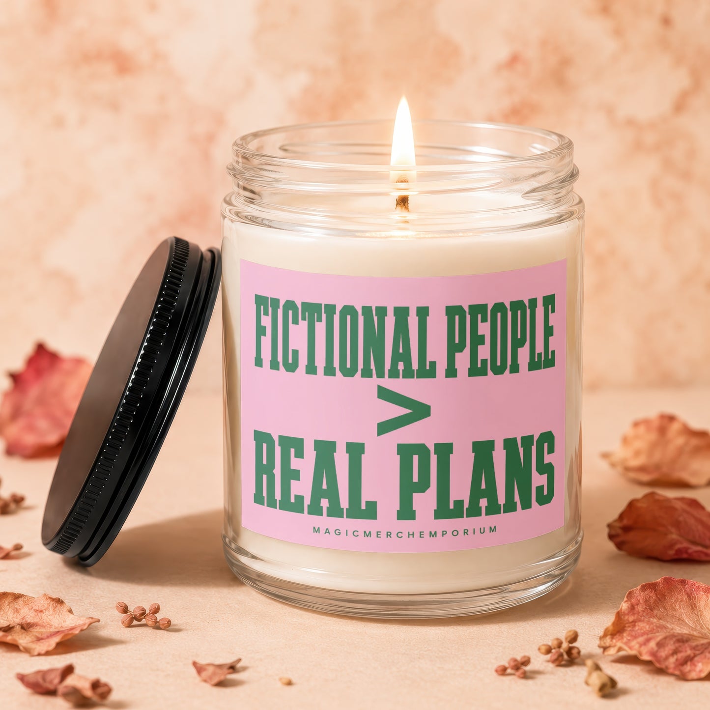 Candle with text "Fictional People > Real Plans" on pink label.