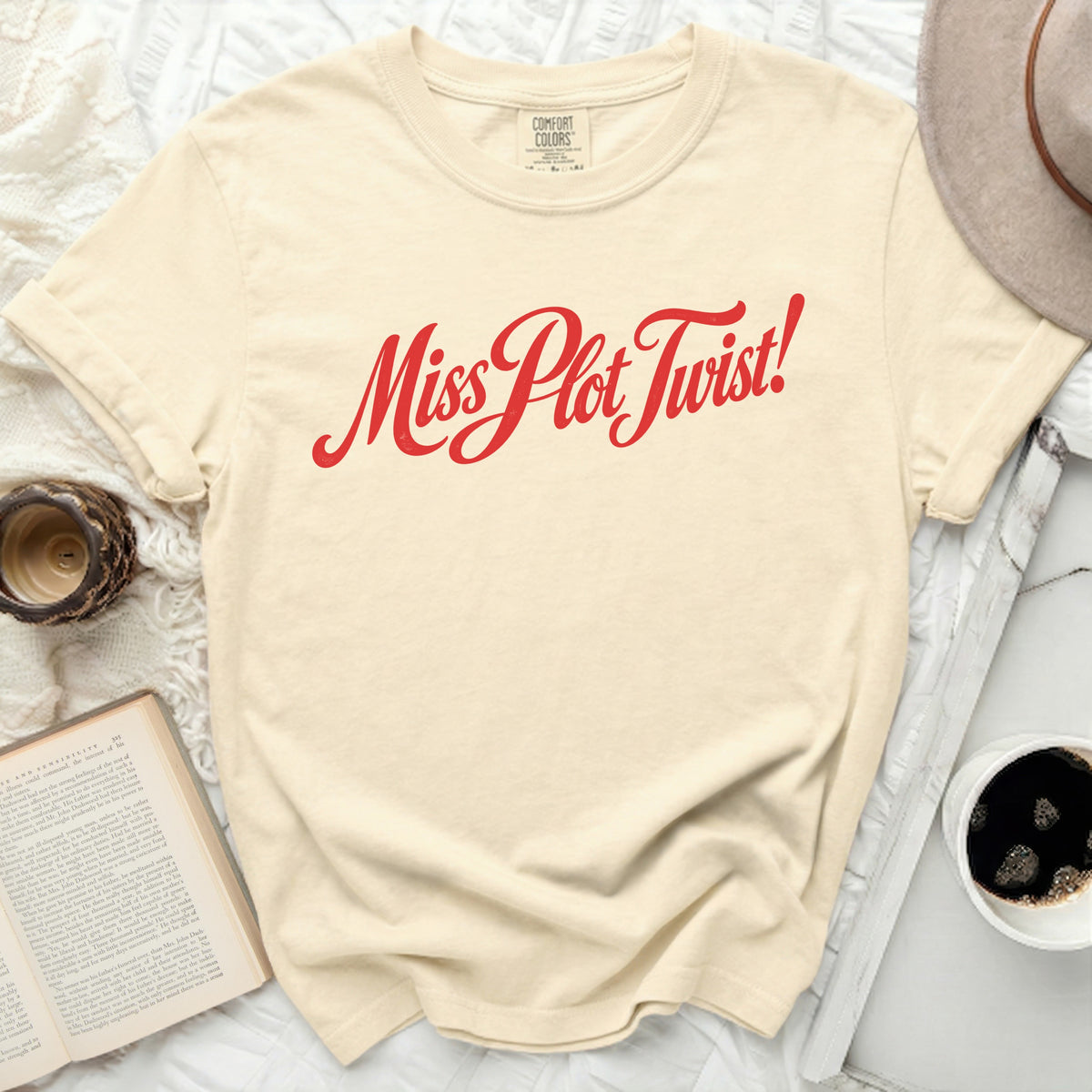 Cream t-shirt with red "Miss Plot Twist!" graphic.