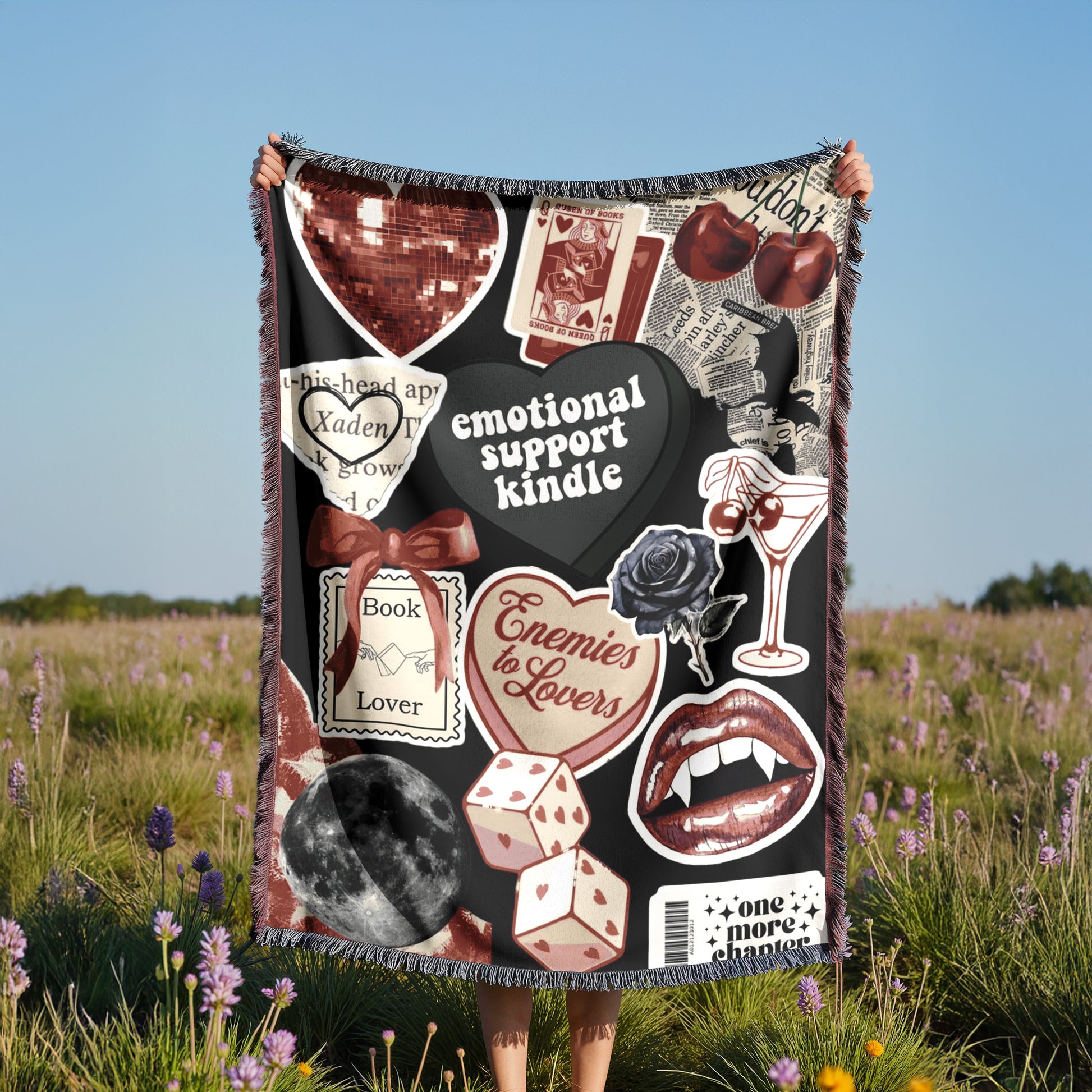 A person is holding up a blanket with various images and text on it, including a heart, a rose, a book, and other symbols.