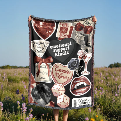 A person is holding up a blanket with various images and text on it, including a heart, a rose, a book, and other symbols.