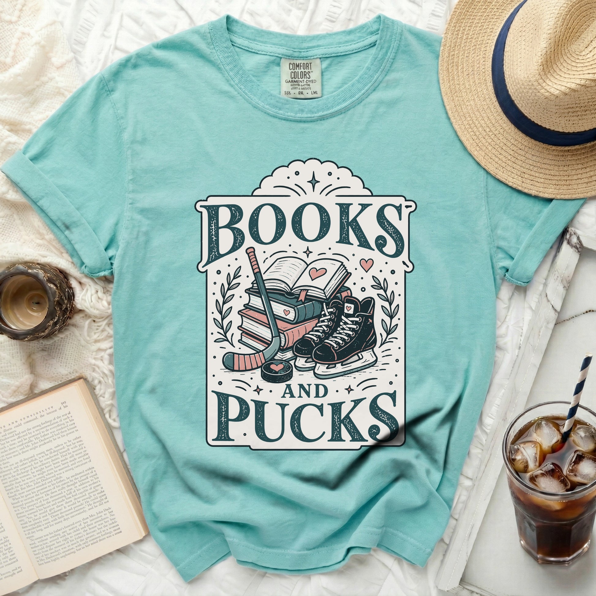 Aqua t-shirt with "Books and Pucks" text, hockey stick, skates, and book.