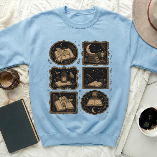 Light blue sweatshirt with a collage of six vintage-style illustrations of books and celestial elements.