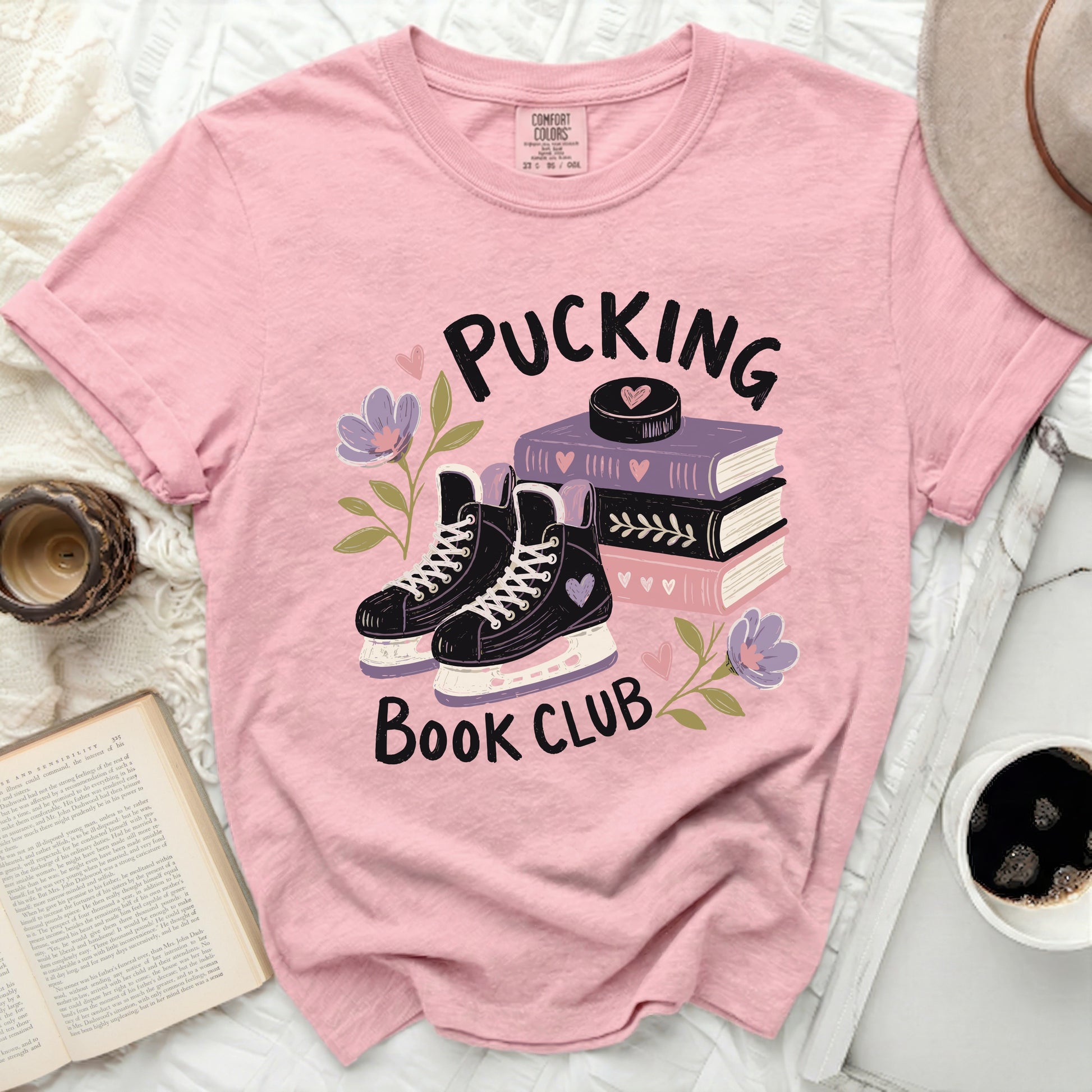 Pink t-shirt with "Pucking Book Club" text, ice skates, and books.