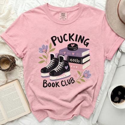 Pink t-shirt with "Pucking Book Club" text, ice skates, and books.